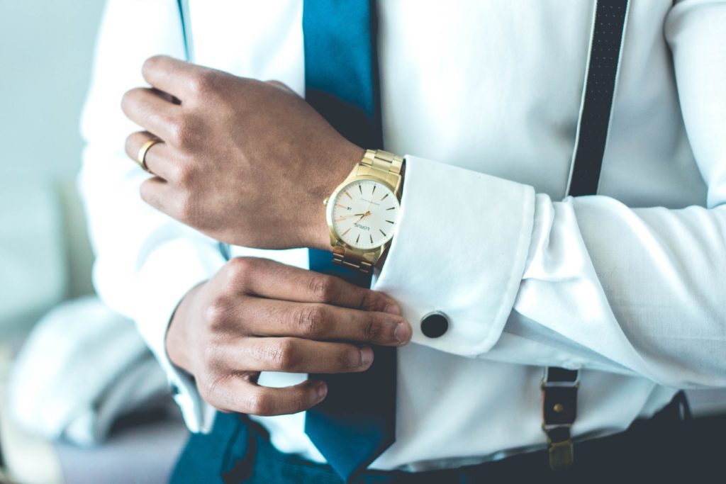 en herre en skjorte og slips og et guld ur med stål lænke på armen